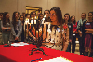 Ellie Aronson, an American Hebrew Academy student, kindles Hanukkah lights in the Temple Emanuel chapel, as peers participate, and Muslim students observe. Photo courtesy of Ivan Cutler